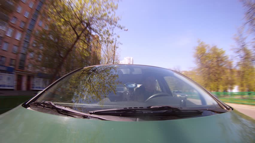 Man goes in green car on cities street, time lapse 
