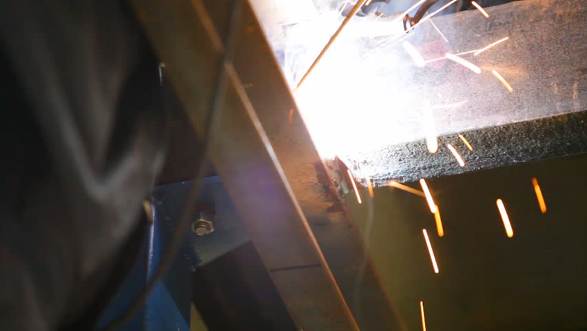Welder is working with metal construction. Close-up of manual hand arc welding machine.