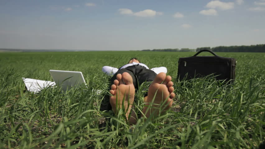 Business man lying on the grass and relaxing forgetting about his usual obligations