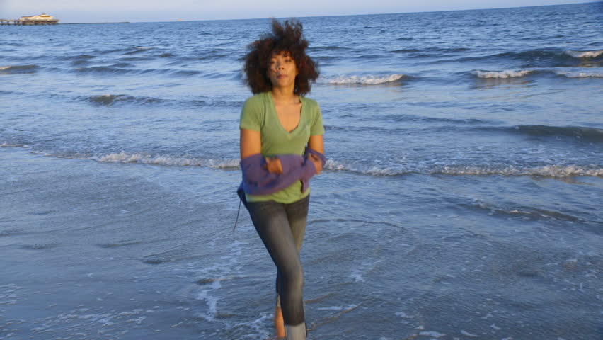 Portrait of woman blowing a kiss and running at beach