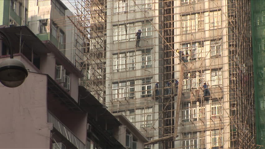 Hong Kong, China - CIRCA April, 2007: Men work on a tall building while supported by a bamboo scaffolding 