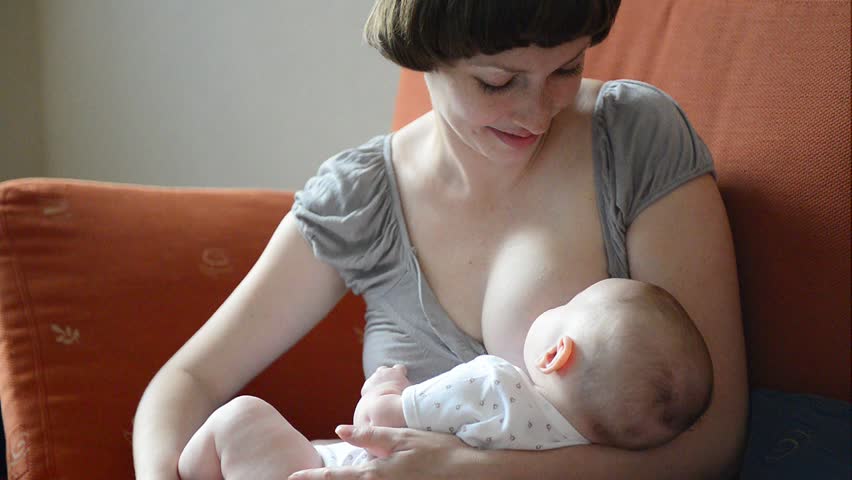 Young beautiful Mother breastfeeding her newborn baby 
