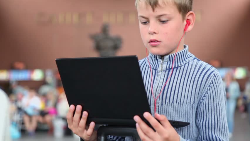 Little boy hold netbook when sits at train station