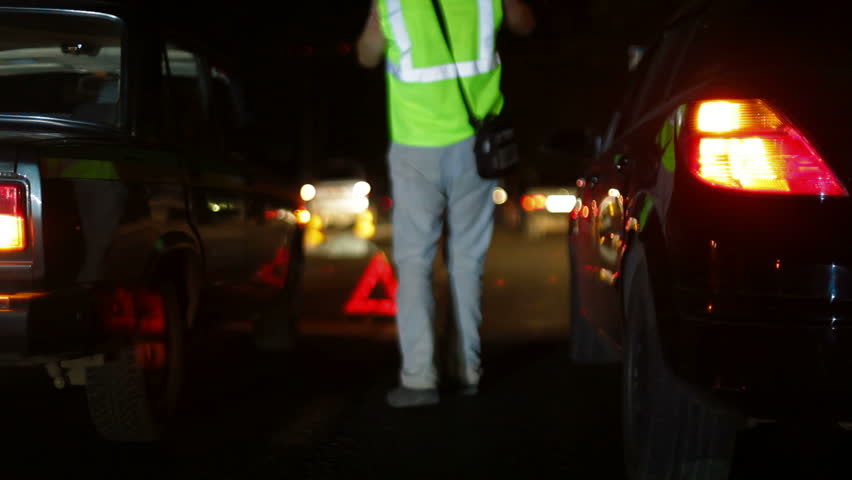 Investigation of the causes of auto accident on the night city road, the dead body of a pedestrian and police officers in the background out of focus