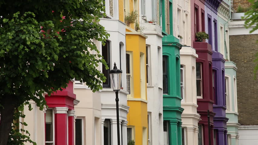 A slow pan down from the sky to real a beautiful cluster of colorful victorian houses in the Notting Hill area of London
