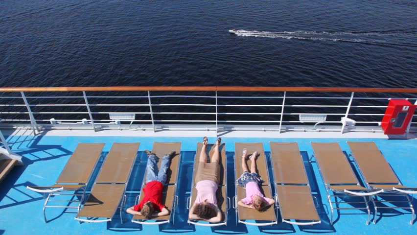 Mother, son with daughter lie in chaise lounge on liner deck