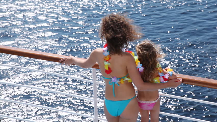 Mother and daughter stand on ship deck in beautiful color garland from flowers in afternoon