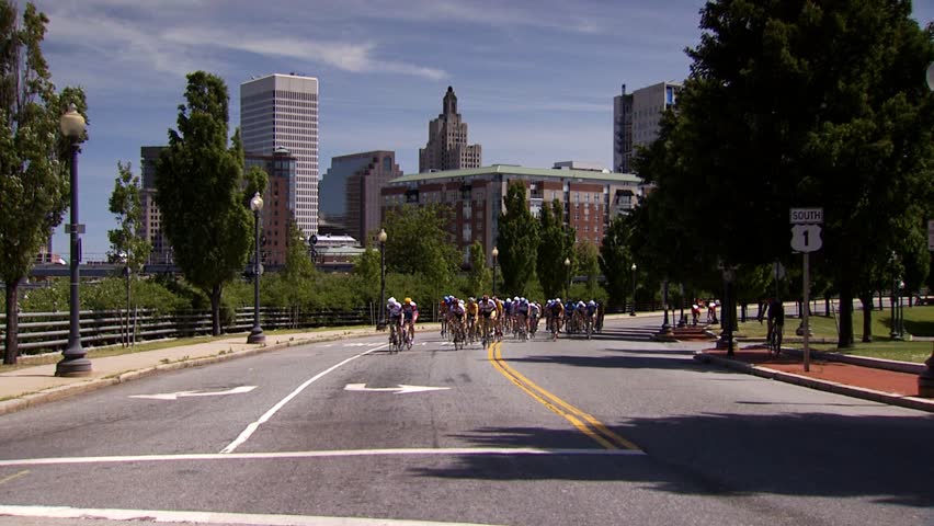 PROVIDENCE, RHODE ISLAND - SEPTEMBER 3, 2009: Large pack of bicycle racers passing camera with city skyline in background