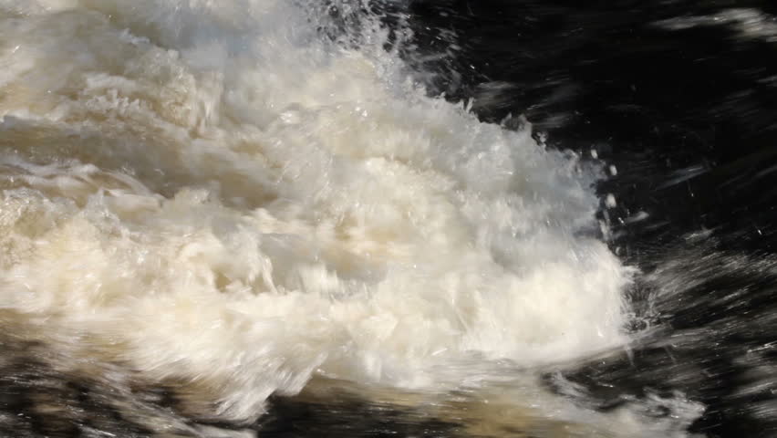 Turbulent white water as a fast river passes over underwater rocks