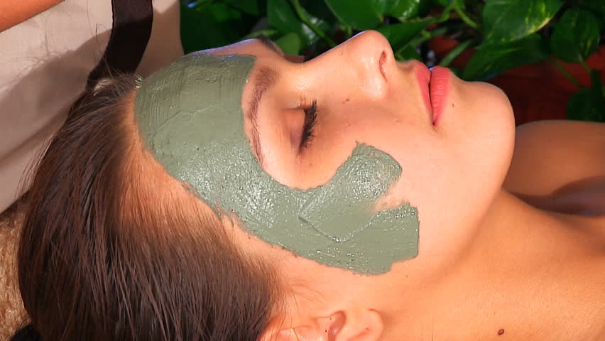 Woman with clay facial mask in beauty spa.