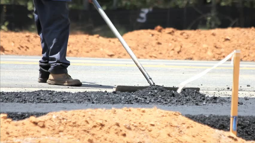 Unknown Highway Construction Worker Raking Loose Asphalt
