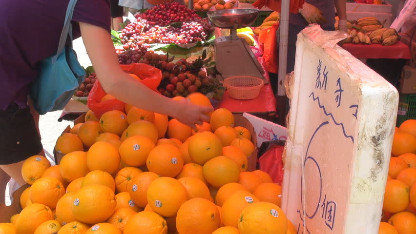 Woman sort orange fruits for buy them, street market, Hong Kong, China
