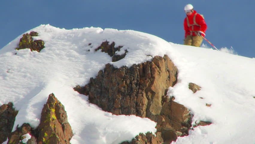 SLOW MOTION - Male skier drops off fifteen foot rock into powder