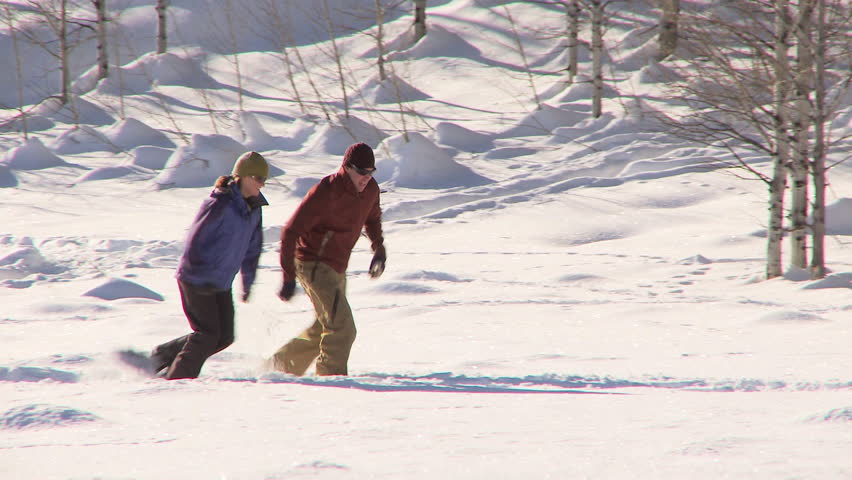 Couple running through the snow with snow shoes on