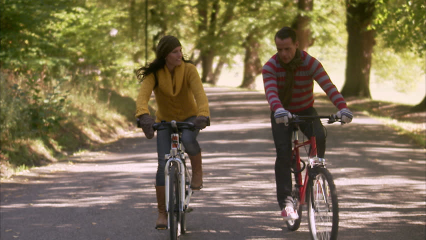 A woman and a man riding a bike an autumn day
