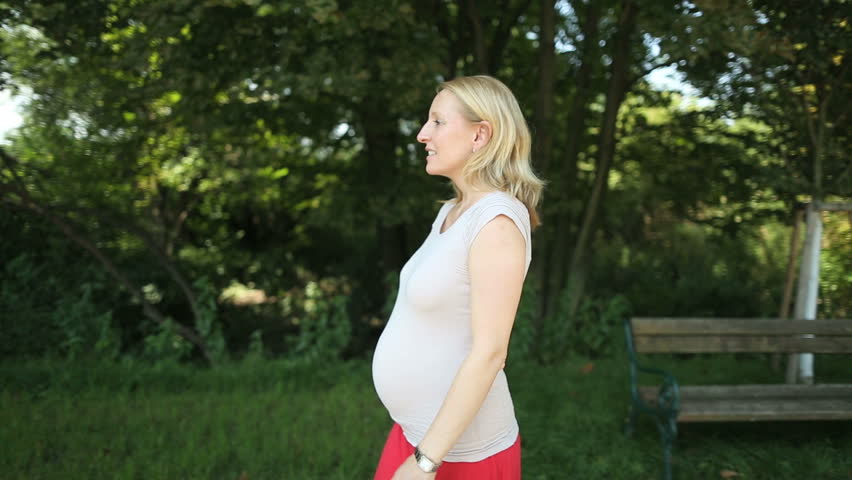 expecting mother walking along trees in summer
