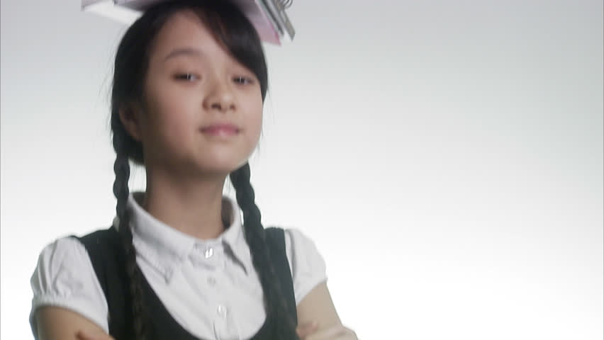 Girl carrying books on her head.