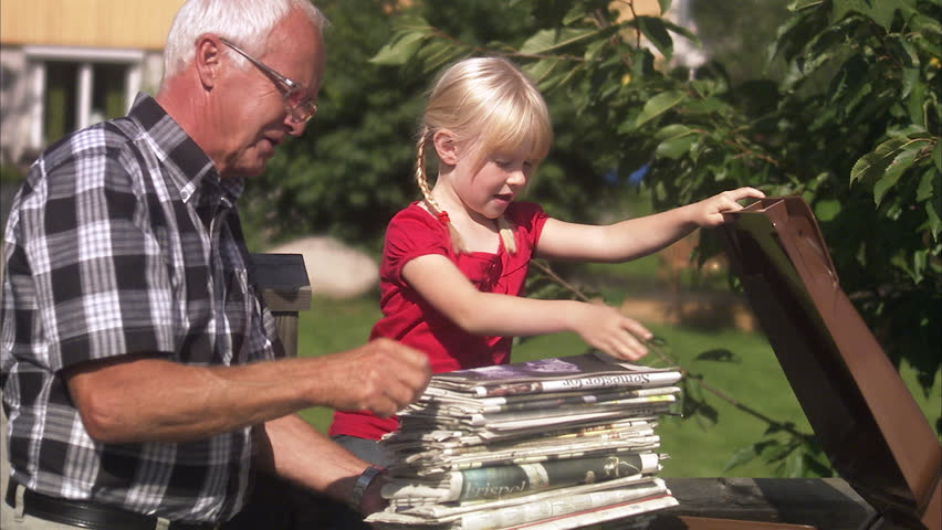 Girl and senior man recycling newspapers