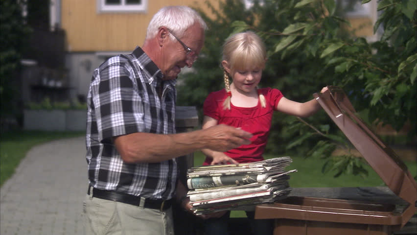 Girl and senior man recycling newspapers
