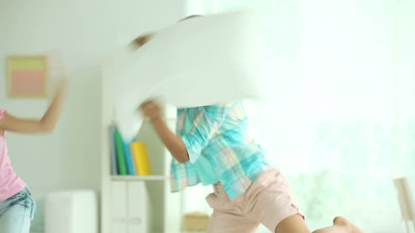 Energetic friends fighting playfully with pillows