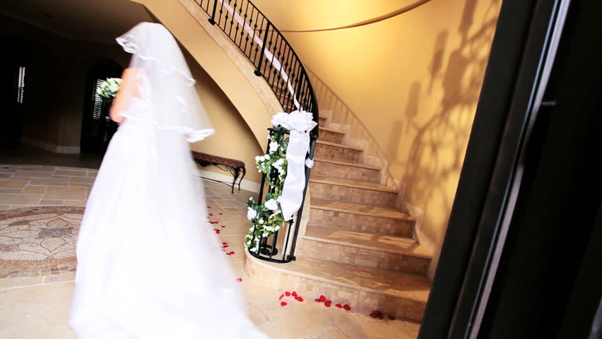 Caucasian brunette female wedding dress and veil descending marble staircase