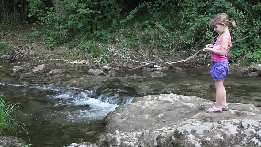 little girl throws stones into the stream