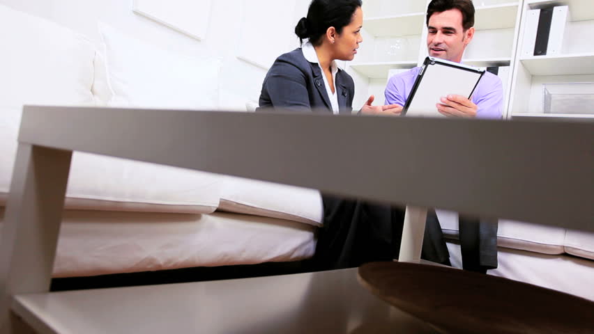 Male business executive informal office meeting with Hispanic female assistant