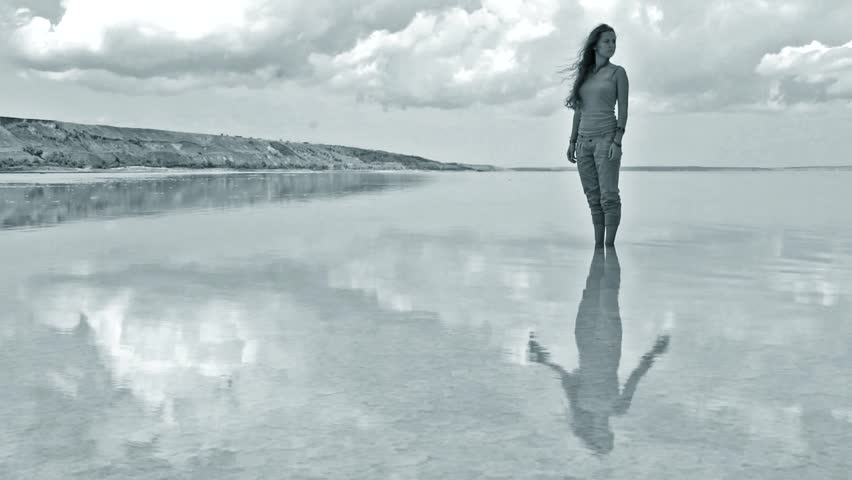 beautiful girl standing in water - stationary image with moving reflection in water