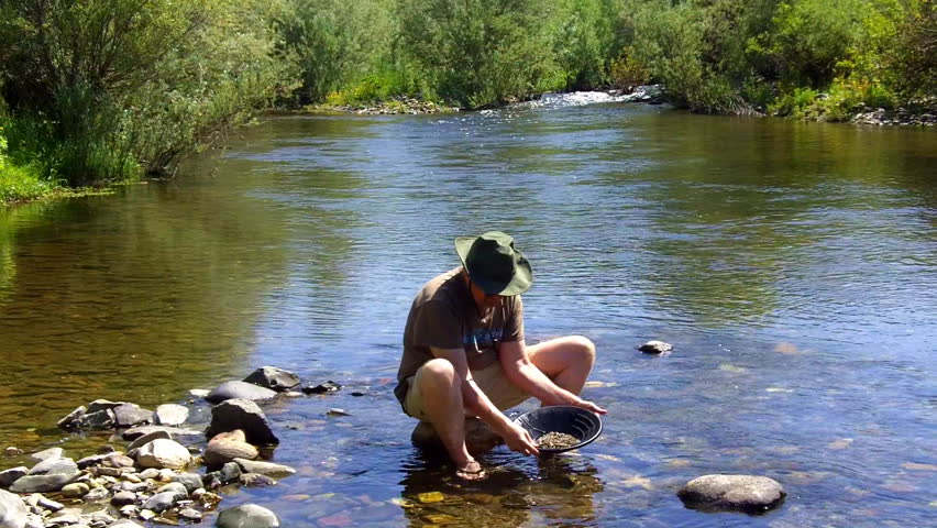 A man pans for gold on the Mokelumne River near San Andrea, CA in the Sierra Nevada Mountain foothills "Gold Country". 