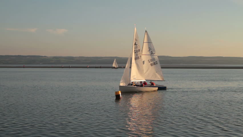 WEST KIRBY, WIRRAL/ENGLAND - AUGUST 9: Two sailing dinghies round a buoy in warm evening light on August 9, 2012 in West Kirby. The Marine Lake is man made coastal lake fed by the sea at high tide.  
