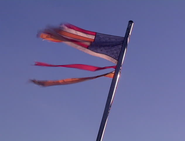 A tattered flag flaps in the wind on a clear blue day. Very disrespectful. DV NTSC video