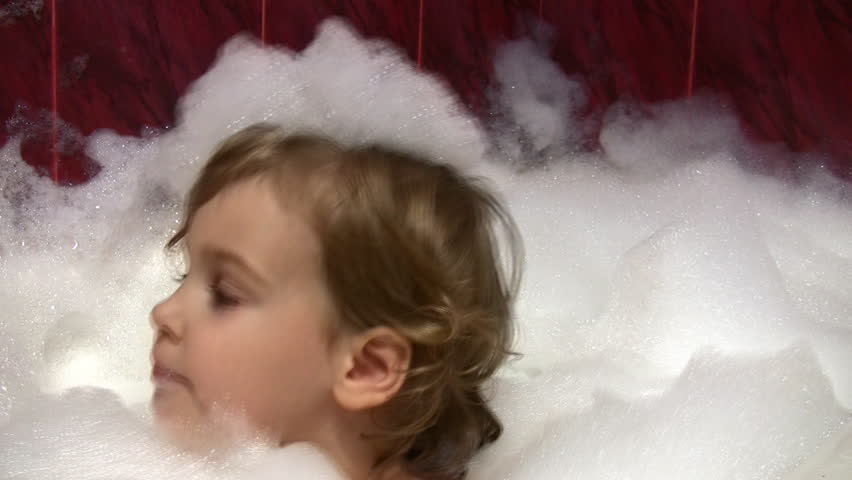 little girl in bath with foam on head 