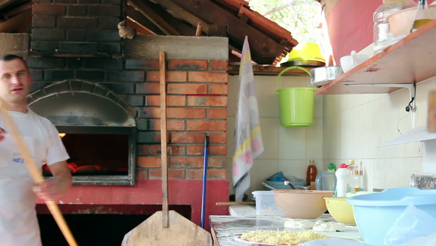 Chef putting pizza in a wood fire brick oven. HD1080p.