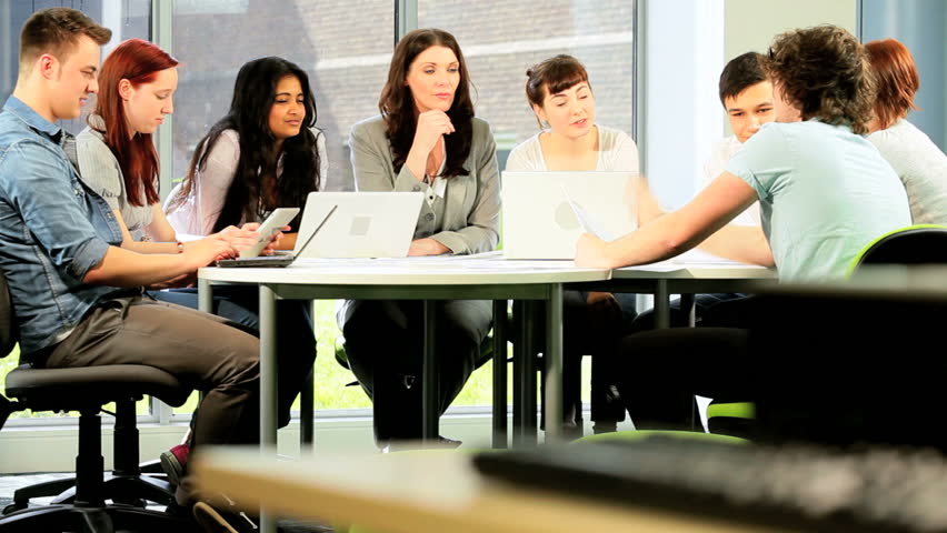 Young Caucasian tutor and university diverse students focus on information online in IT technology room