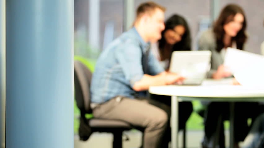Portrait of male Caucasian student e-learning on computer with college diverse classmates in campus library