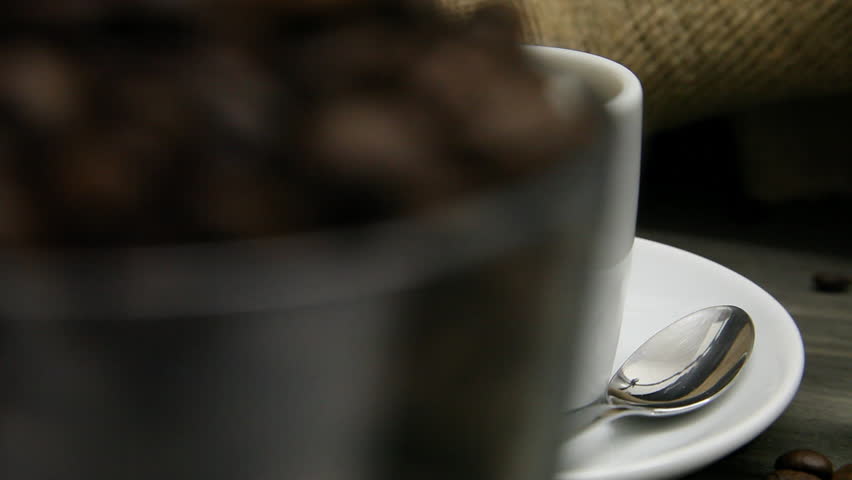 Camera ride from glass of coffee beans to a fresh brewed cup of espresso
