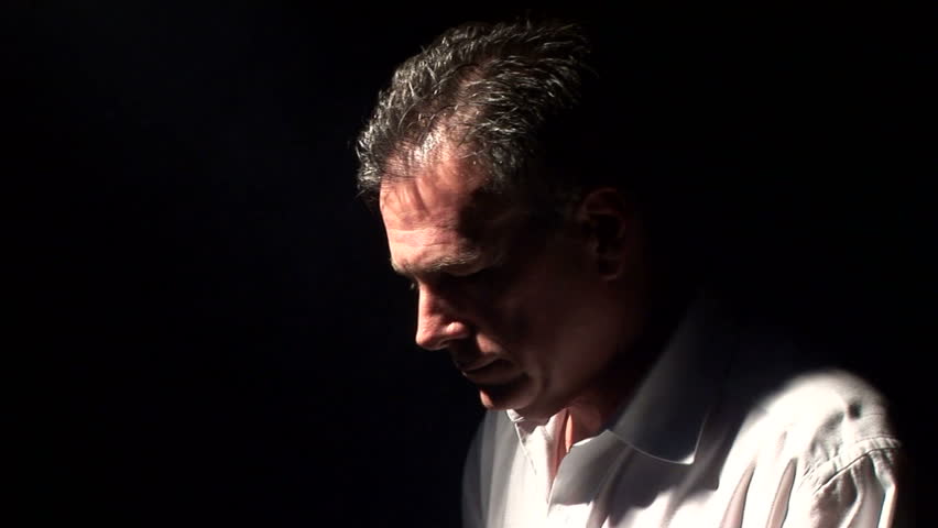man spot lighted by a fog filled beam of light, kneeling in a posture of prayer or meditation