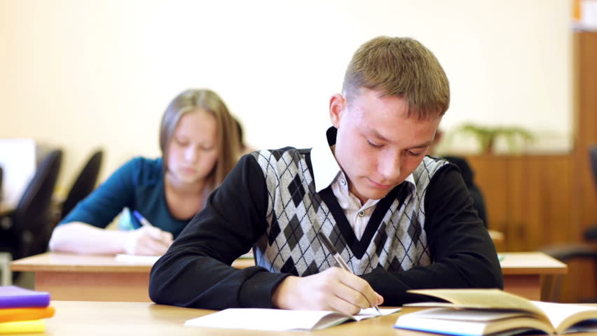 Young angry student sits at the table and shows his frustration