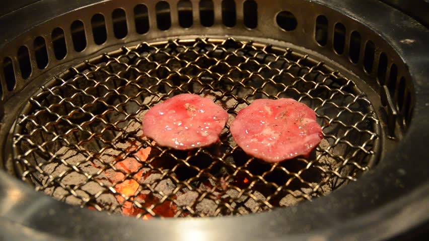 Sliced ox tongue on hot charcoal grill with chopstick