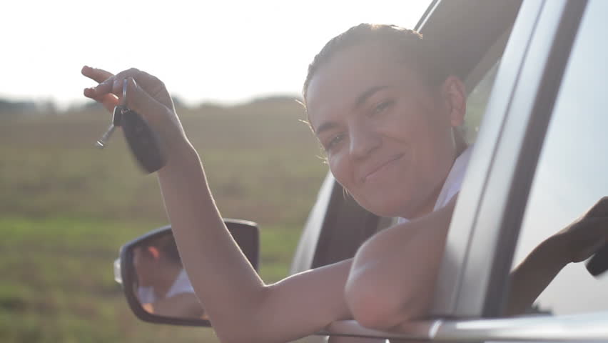 Young businesswoman looking out the car window with keys