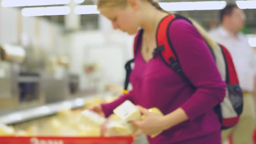 Young woman select cheese in supermarket