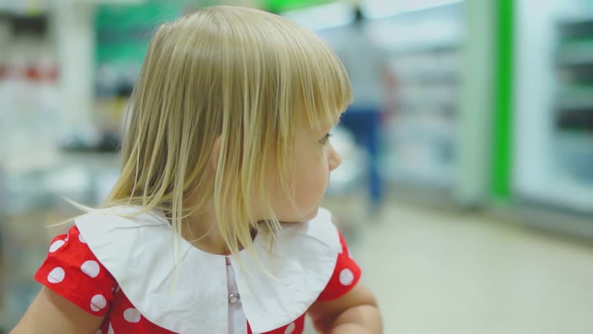 Adorable girl in beautiful dress ride on front side of shopping cart