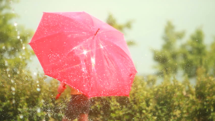 Girl under a red umbrella trying to escape jets of hose water