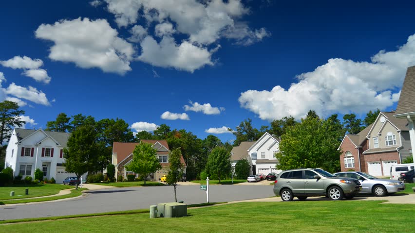 Time lapse of idyllic suburbs with homes on a cul de sac and rolling cumulus clouds on a sunny day timelapse