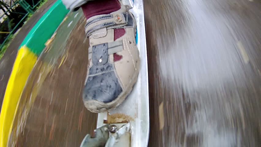 Teenager goes for a drive on scooter on puddles, push away by foot from asphalt