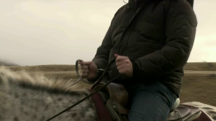 Cadrona, New Zealand, June 2011. Close up of man holding onto reins whilst riding on a horse trek in the historic gold mining valleys and high country farm plateaus of Cadrona
