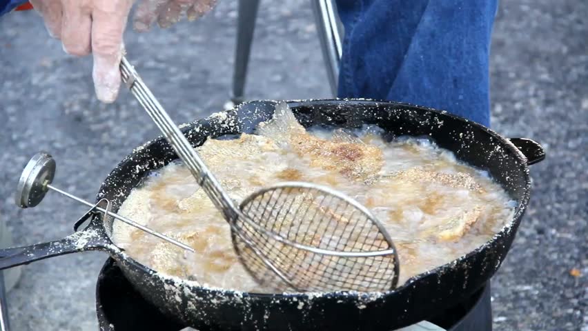 Fish And Cooking Thermometer In Cooking Oil Being Pushed Around With Cooking Utensil 