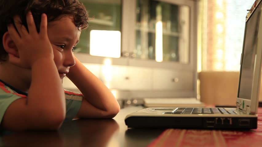 little boy watching notebook and smiling