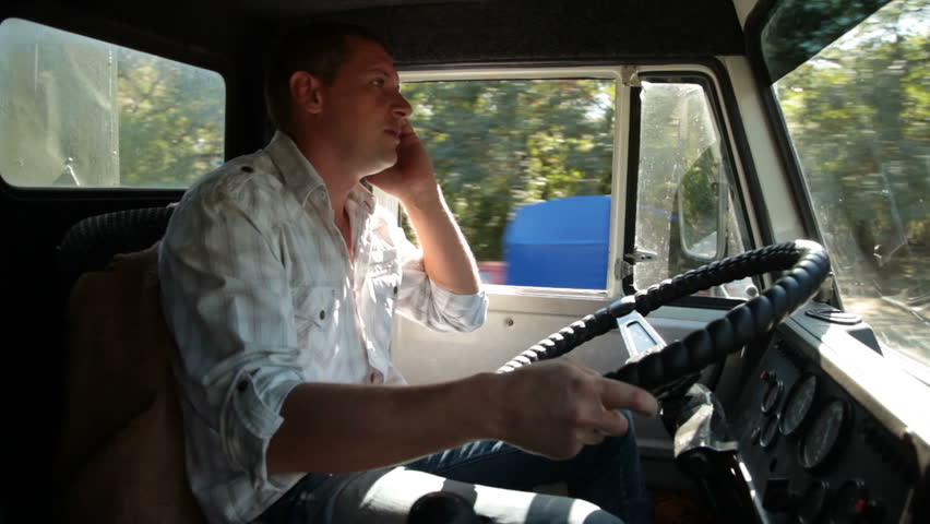 Truck Driver Using Mobile Phone in Cab of Delivery Truck