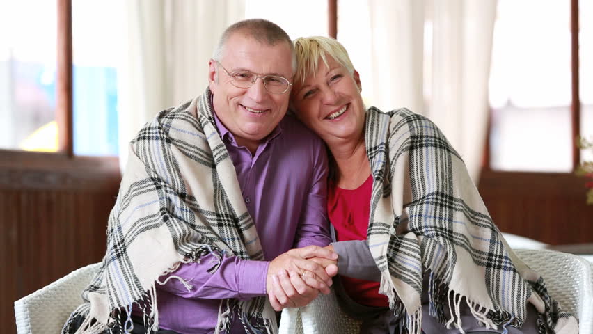 Adorable senior couple sitting together and holding hands